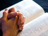 folded hands on an open bible in devotion folded hands on an open bible in devotion