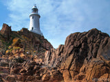 tall light house in the background of the rock cliffs tall light house in the background of the rock cliffs