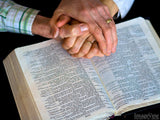 hands joined over an open bible hands joined over an open bible