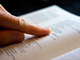 single finger points to a scripture with bible in background single finger points to a scripture with bible in background