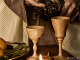 wine being poured into old wooden cups wine being poured into old wooden cups