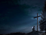 young man at worship at the cross in evening light