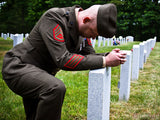 soldier kneels at tombstone in remembrance