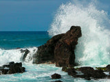 waves crash over rock formation creating spray