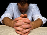 man with folded hands head bowed in prayer