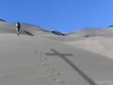 footprints in the sand beside a cross shadow