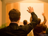 man in church raises hands in praise