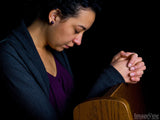 women prays in church with hands on pew