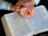 hands joined over an open bible