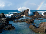 ocean rocks crashing waves and rainbow in background