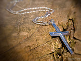silver cross pendant on wood background