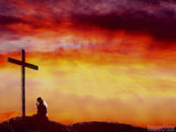 man kneeling at a cross during sunset