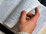 closeup of hand turning a bible page the word