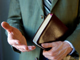 man with extended hand and bible welcomes to church service