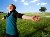 woman in field worships with arms out